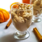 Pumpkin Pudding in a glass on a white table with cinnamon and pumpkin.