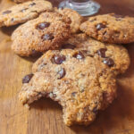 Paleo chocolate chip cookies on a table. One bite bitten out of one cookie.