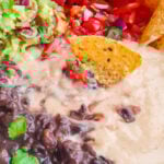 Best vegan queso with bean, guacamole, pico de gallo and tortilla chips in a white bowl.