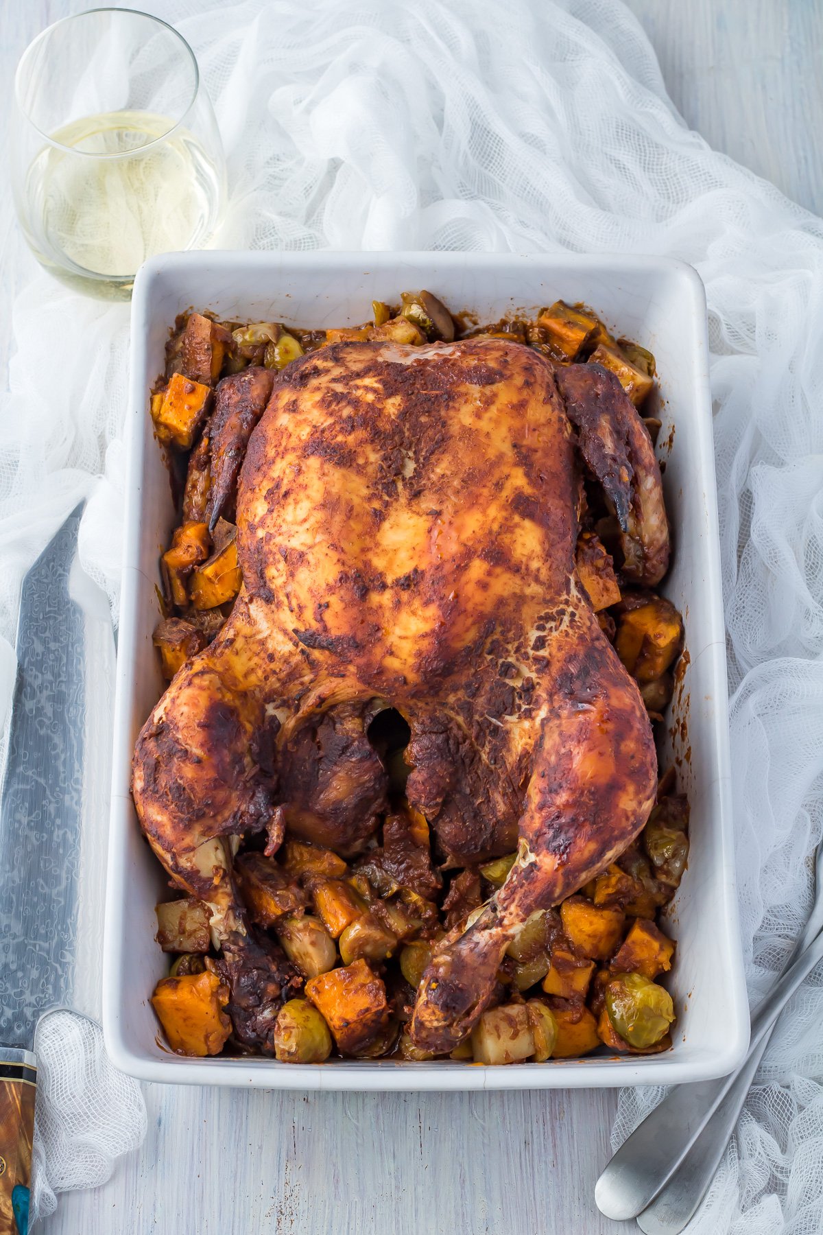Slow roasted chicken in a white casserole dish with vegetables.