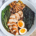 Overhead shot of gluten free chicken ramen in a white bowl with a white cloth.