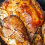 Whole roasted citrus turkey in a black baking tray.