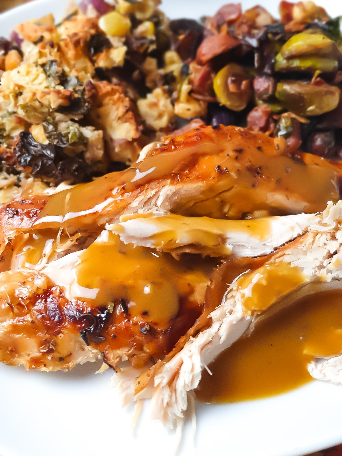 Gluten-free turkey gravy over turkey on a white plate with vegetables.