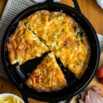 Ham and cheese frittata in cast iron skillet on wooden table, overhead shot.