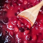 Overhead shot of a wooden spoon in a pot of sugar free cranberry sauce.