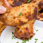 Keto chicken wing being dipped in a creamy dip.
