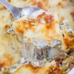 Serving spoon lifting green bean casserole out of casserole dish.