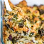 A serving spoon serving keto stuffing from a glass casserole dish.