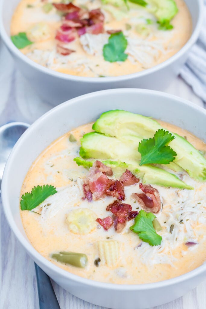 Two bowls of keto chicken chili with avocado and bacon.