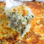 Spoon lifting crack chicken casserole out of the baking dish.