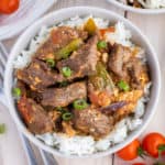 A bowl of Chinese beef curry with rice and tomatoes.