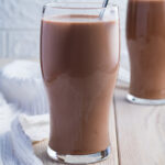 2 glasses of Keto Chocolate milk on a table with a metal straw.