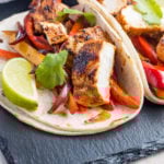 Authentic Mexican chicken fajitas with peppers and lime wedges.