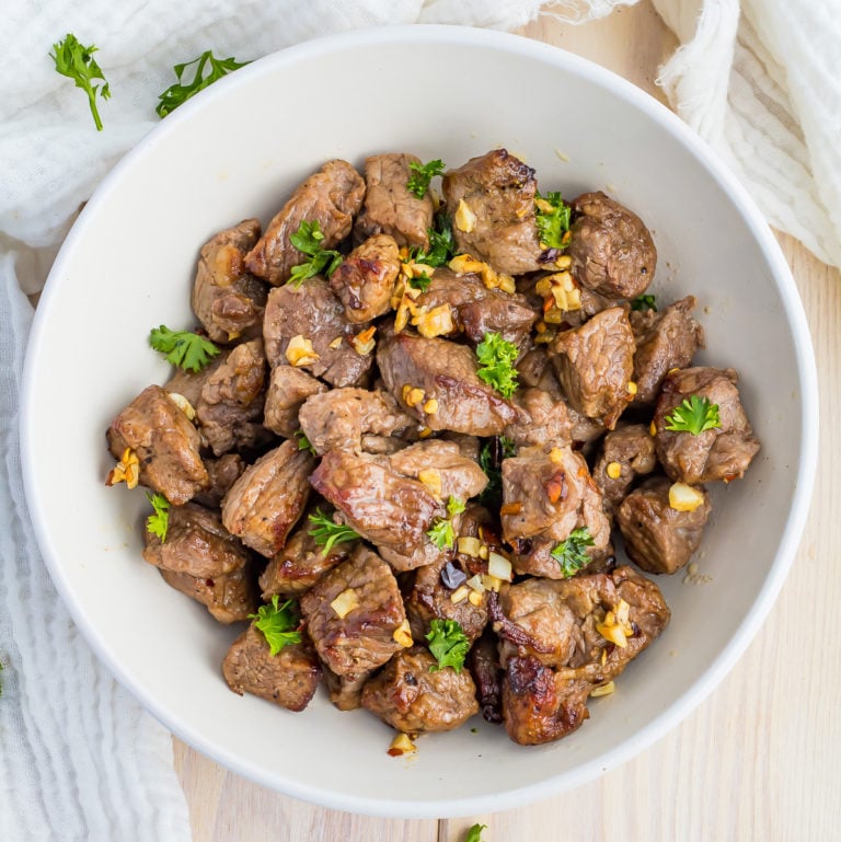 Succulent Air Fryer Steak Bites served in a white bowl garnished with parsley.