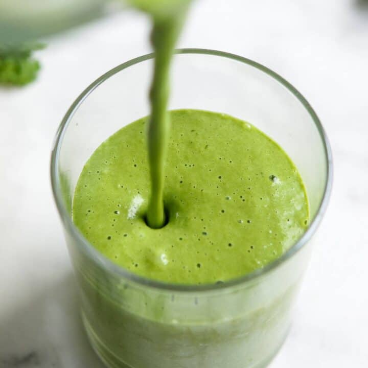 A green smoothie being poured into a glass.