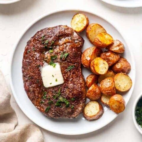 Steak on a plate with potatoes and butter.