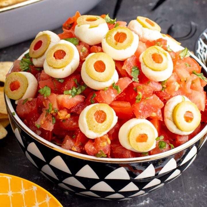 A bowl full of tomatoes and chips with eyeballs on them.