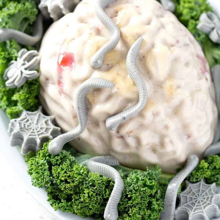 A white plate with broccoli and worms on it.