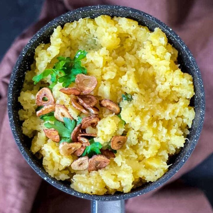 A spoon full of soup with carrots and potatoes.