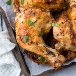 Air Fryer Chicken legs on a metal tray with parchment paper next to a white cloth.