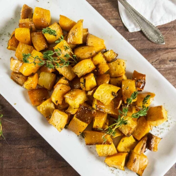 Roasted butternut squash on a white plate with thyme, perfect for rutabaga recipes.