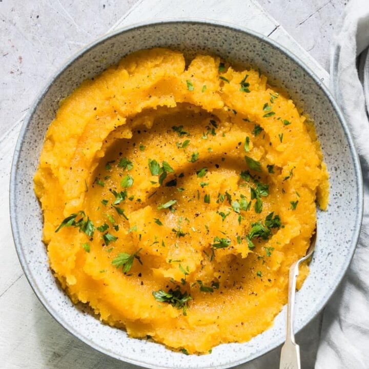 A bowl of sweet potato mashed potatoes with parsley and rutabaga.