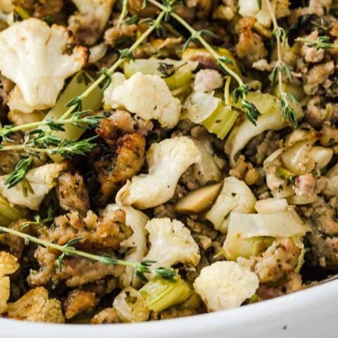 A white casserole dish filled with Keto stuffing and thyme.