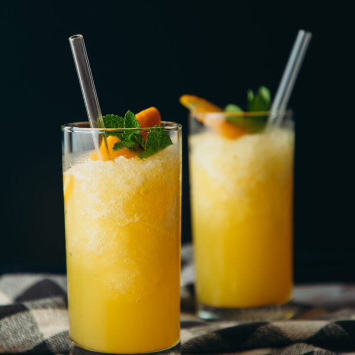 Two glasses filled with orange juice and mint.
