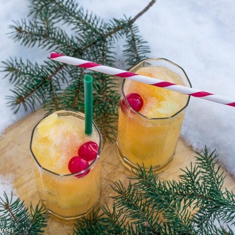 Two glasses of orange juice on a snow covered table.