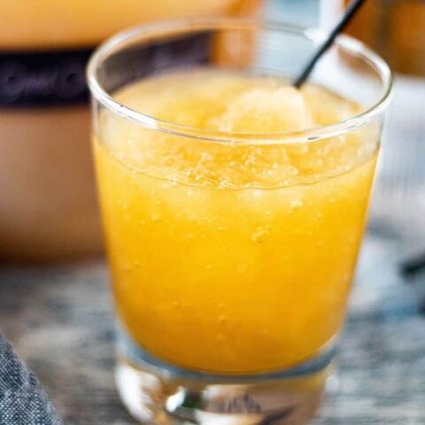 A glass of orange juice with a straw in it.