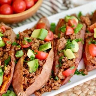 Sweet potato tacos on a plate with tomatoes and avocados.