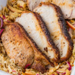 Side shot of air fryer pork and sauerkraut in a white casserole dish.