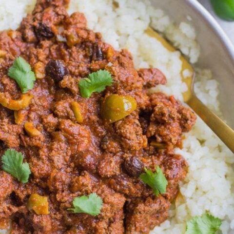A bowl of rice with meat and peppers on it.