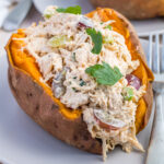 Whole30 Chicken salad on a sweet potato on a grey plate.