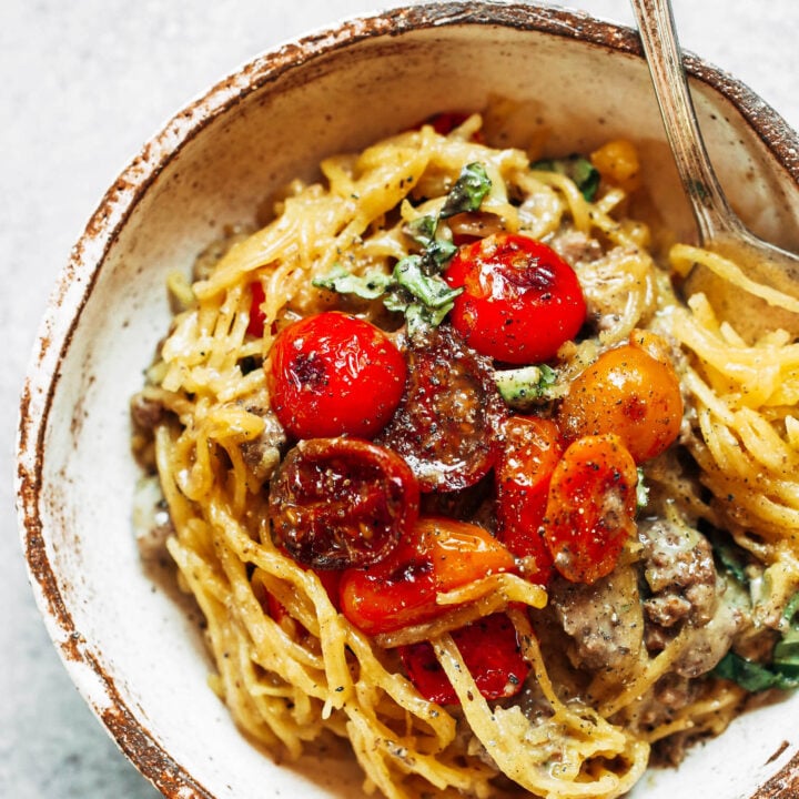 A bowl of spaghetti with meat and tomatoes.
