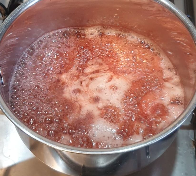 Strawberries boiling in a pot of water.