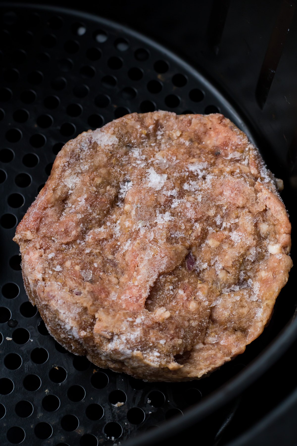 Frozen hamburger in an air fryer.