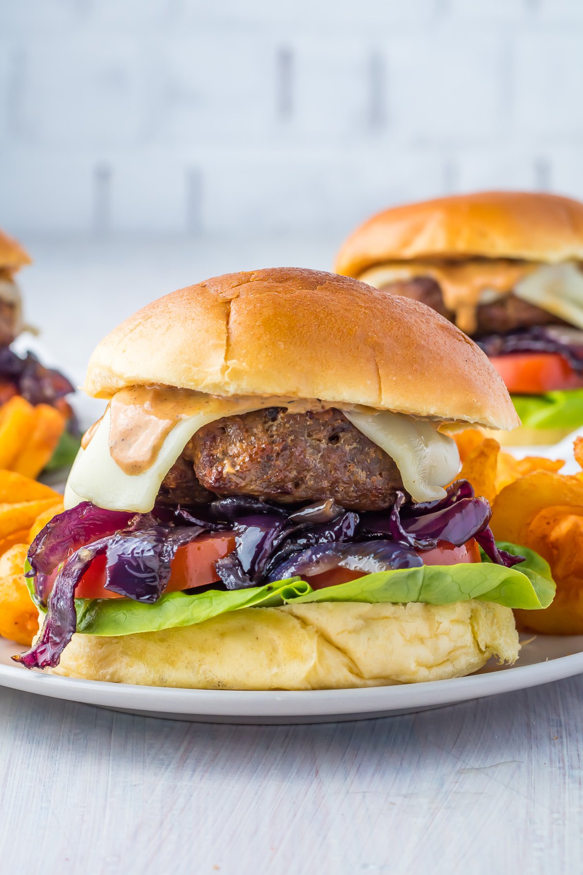 Hamburger with sauteed onions. Two hamburgers in the background.