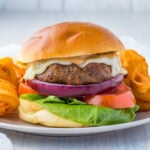 Worcestershire sauce burgers on grey plates with curly fries.
