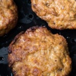 Three burgers are being cooked on a grill, while one is reheated in an air fryer.