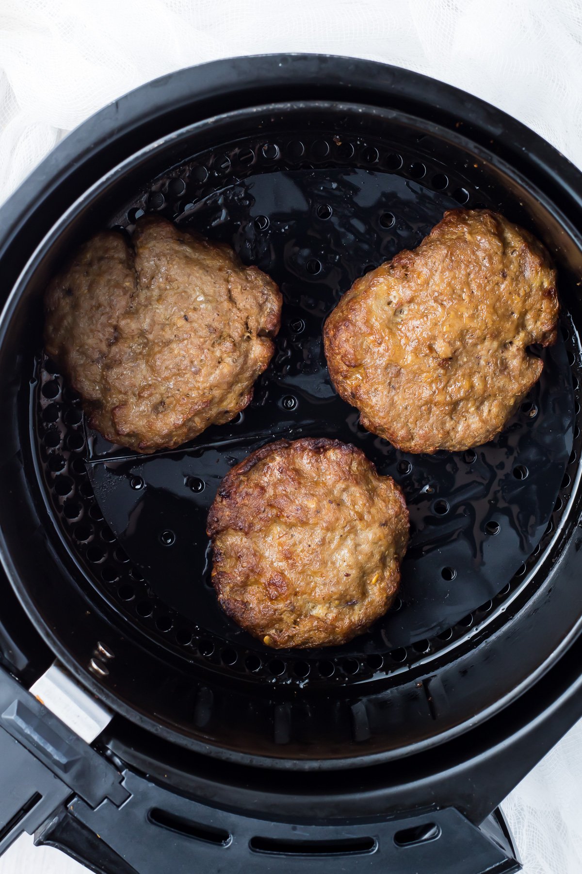 Overhead shot of reheated burgers in an air fryer.