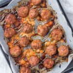 Overhead shot of baked meatballs on a parchment paper-lined baking sheet.