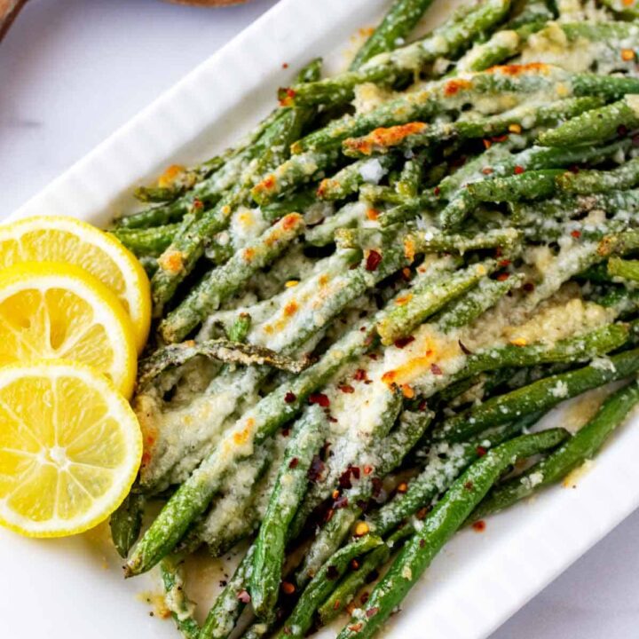Low Carb Thanksgiving Side Dish: Green beans on a white plate with lemon wedges.