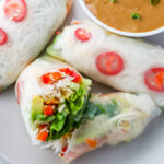 Photo of salad rolls on a grey plate with peanut dipping sauce.