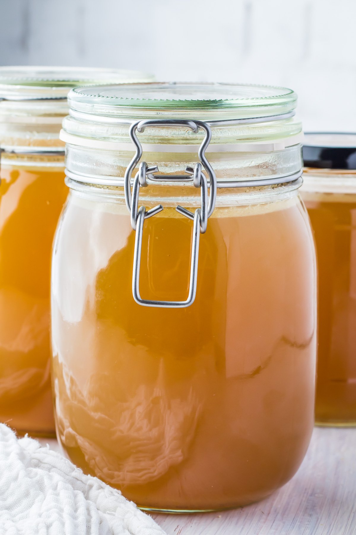 Three jars of ham stock on a table.