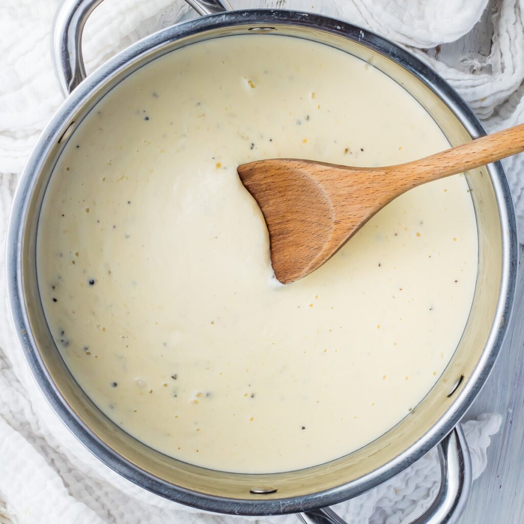Overhead photo of keto alfredo sauce in a pot with a spoon.