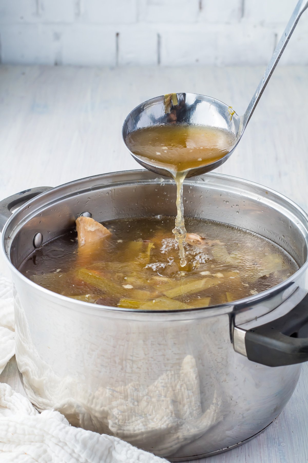 A ladle pouring ham stock into a pot.