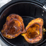 Two acorn squash cooked in an air fryer.