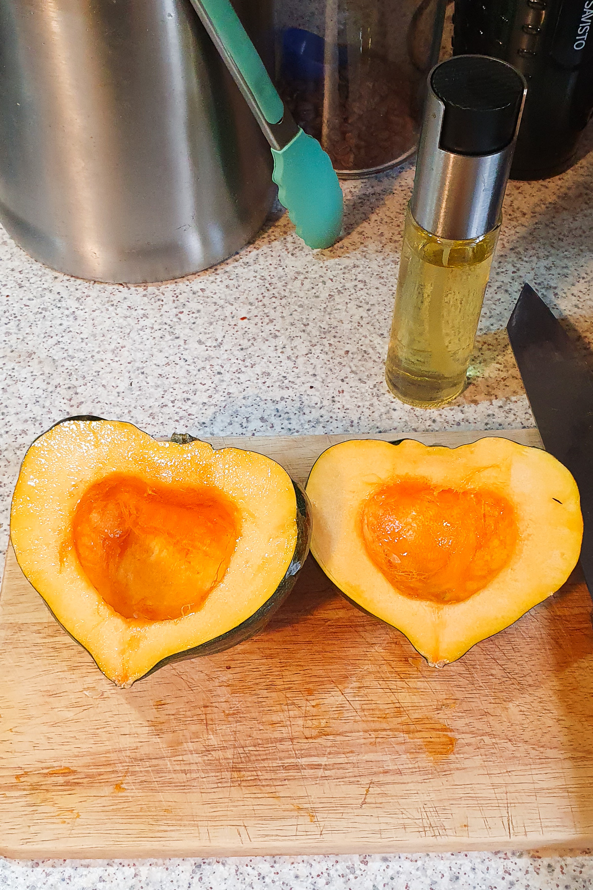 Oil sprayed on two halves of an acorn squash.