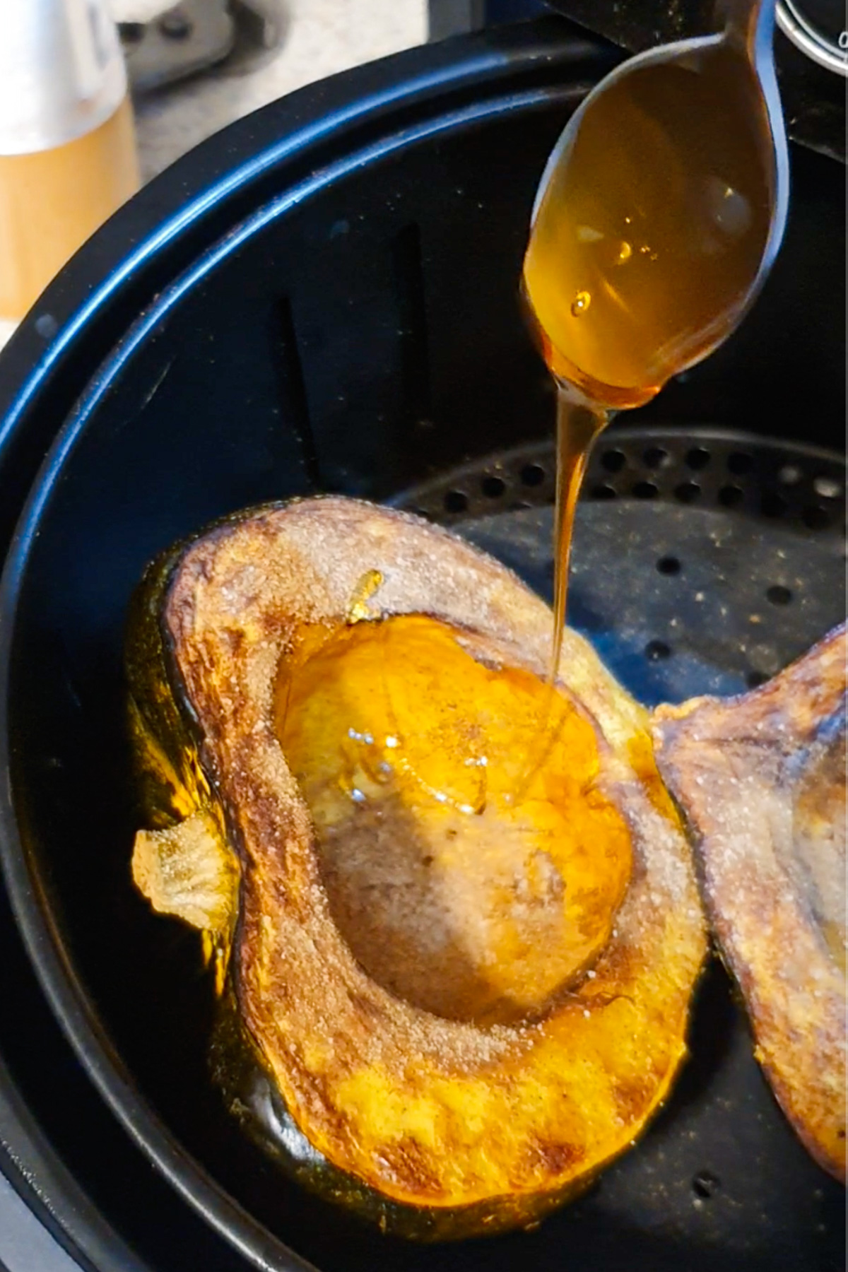 Drizzling honey over an acorn squash in the air fryer.